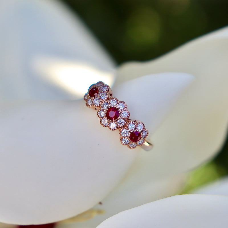 Rose gold diamond ring with ruby gemstones on a white flower petal