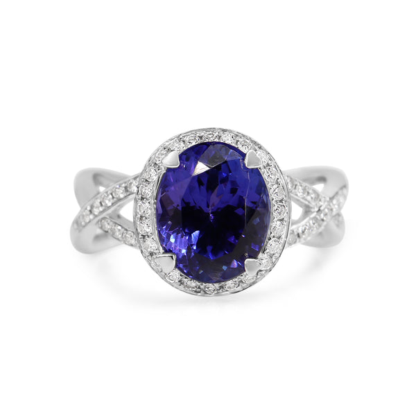 An 18ct white gold tanzanite and diamond halo and twist ring with a large blue tanzanite centerpiece surrounded by smaller clear diamonds.